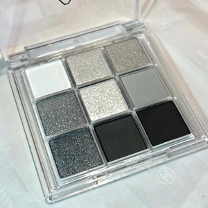 Macro view of 9-color eyeshadow palette with matte grey, black and silver glitter shades