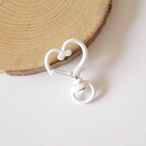 Detailed view of heart-shaped white lacquer lobster clasp on a natural wood block