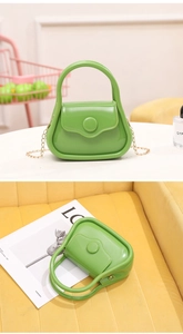 Detail of neon green PVC jelly mini bag with golden metal chain strap and round buckle
