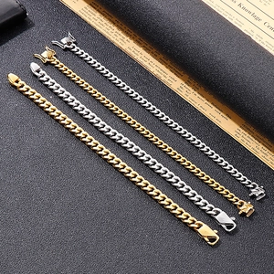 Close-up of gold and silver Cuban link chains with box clasps on a dark textured background