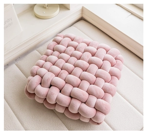 Detailed macro view of pink square hand-woven textured decorative cushion on beige carpet