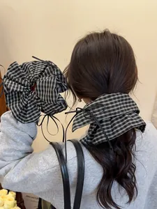 Detail of a large black and white plaid scrunchie with elegant long black ribbon ties