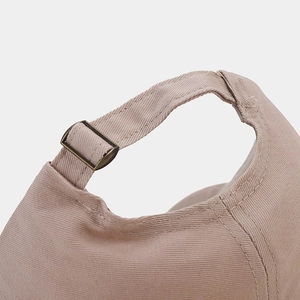 Detail of adjustable metal buckle and cotton twill texture on beige baseball cap
