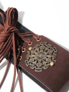 Detail of brown faux suede lace-up corset belt with bronze hollow metal ornament