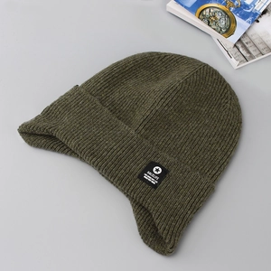 Detailed close-up of army green ribbed knit beanie with star brand patch and thick texture