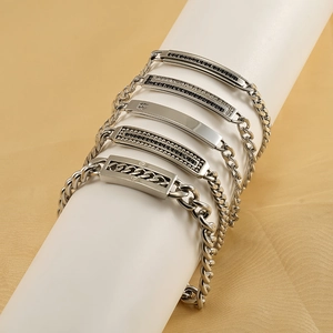 Detailed close-up of various silver titanium steel Cuban chain bracelets on display