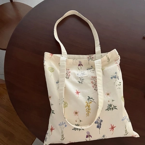 Detailed view of beige canvas tote bag with floral prints on a dark wood table
