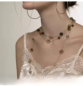 Close-up of three-layer layered necklace with colorful crystal beads and gold rings