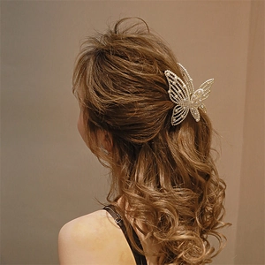 Detail of elegant metal butterfly hair claw with pearl inlay on woman's hairstyle
