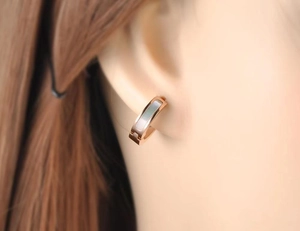 Gros plan d'une boucle d'oreille en acier inoxydable doré 18K avec nacre blanche