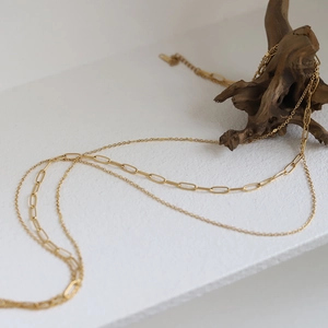 Minimalist double-layered gold titanium steel necklace with paperclip chain on white wood