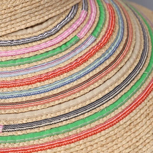 Close-up of woven raffia sun hat with colorful striped ribbon details and fiber texture