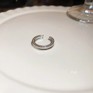Gros plan d'un earcuff double couche en argent avec zircons sur une assiette blanche