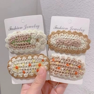 Detailed close-up of four handmade crochet flower hair clips on a jewelry display card