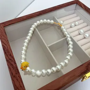 Detail view of pearl beaded necklace with a cute yellow duck pendant in a jewelry box