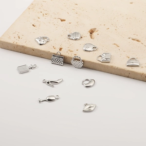 Macro shot of silver metal charms in shapes of handbag, stiletto heel, heart, and lips