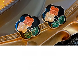 Detailed close-up of retro floral stud earrings with black enamel and gold metal edges