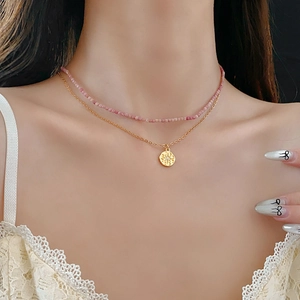 Détail d'un collier à deux rangs avec perles roses et pendentif doré sur un modèle