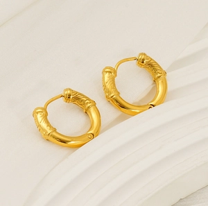 Detailed view of golden hoop earrings with intricate spiral texture and clicker closure