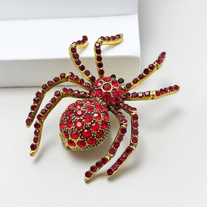 Macro view of gold spider brooch featuring vibrant red rhinestones and intricate leg details
