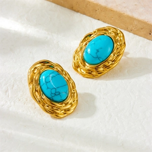 Vintage gold oval turquoise earrings set with intricate woven edges on a stone surface