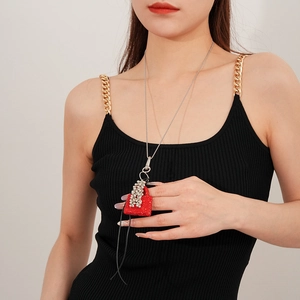 Détail d'un pendentif sac en strass rouges avec pompons argentés et fine chaîne longue