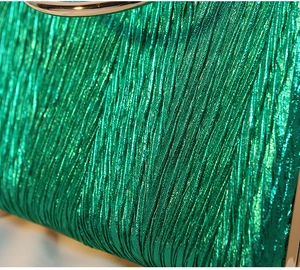 Macro view of emerald green metallic pleated fabric with a golden ring handle