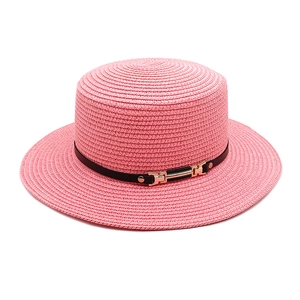 Détail d'un chapeau de paille rose à toit plat avec ruban noir et boucle H dorée