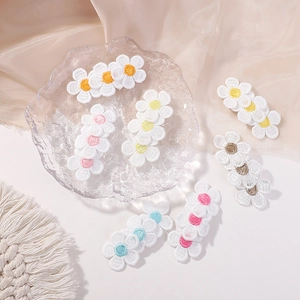 Détail de barrettes à fleurs brodées avec pétales blancs et cœurs colorés variés