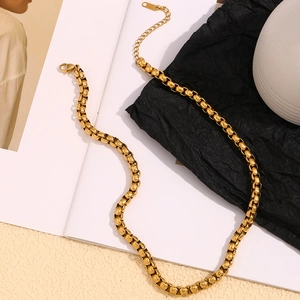 Detail view of 18K gold plated snake chain necklace with lobster clasp on magazine backdrop