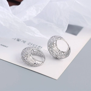 Macro detail of S925 sterling silver hoop earring with intricate hollow patterns