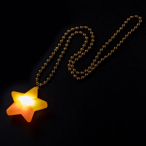 Close-up of a glowing yellow star pendant on a golden chain against a dark background