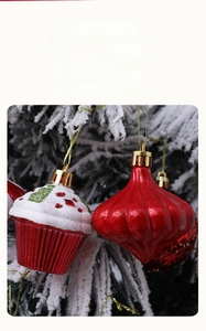 Close-up of red Christmas cupcake and onion-shaped ornaments hanging on snowy tree