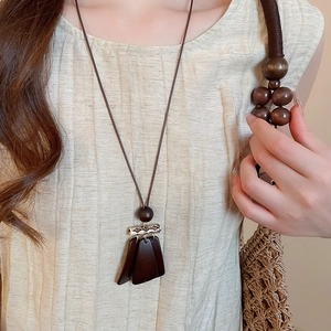 Close-up of vintage long necklace with trapezoidal wood pendants and metallic accents