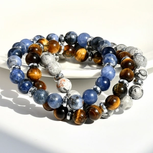 Drei Naturstein-Armbänder mit Tigerauge und Sodalith auf weißem Teller im Detail