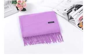 Detail view of a purple cashmere scarf with fringes, styled with elegant floral accessories