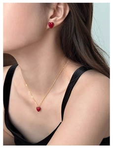 Close-up of model wearing gold necklace and red heart zircon earrings jewelry set