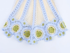 Détail de l'ourlet au crochet avec motifs floraux bleu clair et beige tricotés