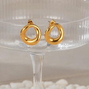 Detail of gold mobius loop earrings hanging on a glass container with white stones