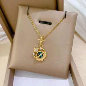 Close-up of golden star and planet pendant with blue stones on beige silk padding