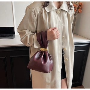 Close-up of deep burgundy PU leather bucket bag with drawstrings and golden metal buckle
