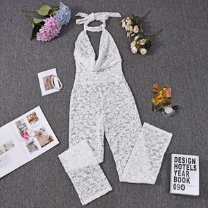 Flat lay of a white lace halter neck jumpsuit with floral texture and lifestyle props