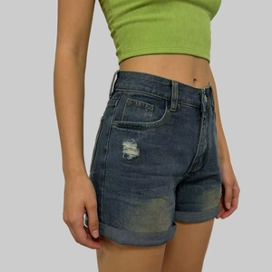 Dettaglio di pantaloncini di denim blu scuro a vita alta con orli arrotolati e strappi