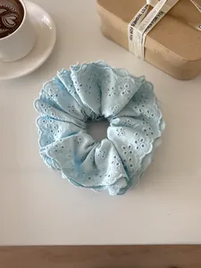 Detail of light blue lace embroidery scrunchie with delicate floral cutout pattern