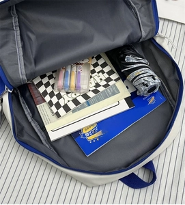 Top view showing the large capacity interior of the blue and white backpack with items