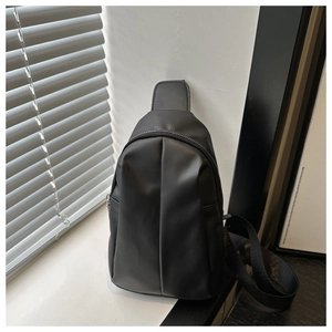 Close-up of black leather chest bag with vertical pleats under soft blind shadows
