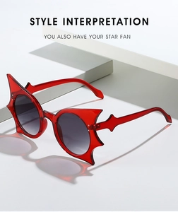 Detailed view of red bat wing sunglasses with dark gray gradient lenses on geometric stands