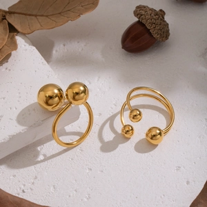 Minimalist stainless steel open ring with gold spheres on textured geometric props