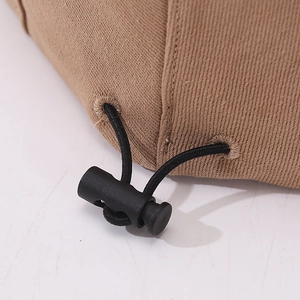 Detail of adjustable black drawstring toggle on khaki twill baby beret hat