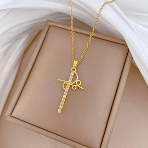 Macro detail of gold cross pendant with clear crystals on a beige leather jewelry box